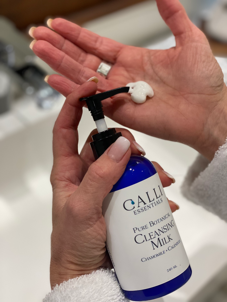 Woman pumping cleansing milk by Calli Essentials into the palm of her hand